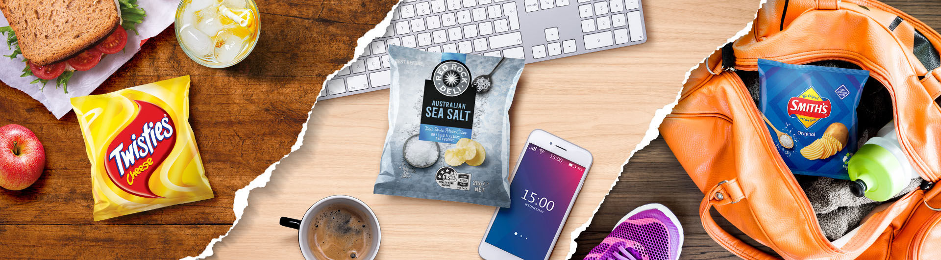 Pack of Twisties next to a sandwich, pack of Red Rock Deli next to a keyboard, pack of Smith's in a bag. 